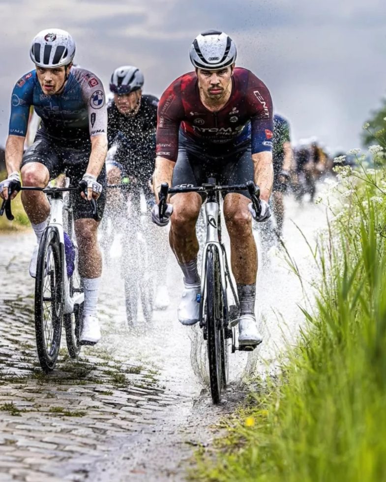 Joshua racing on wet cobblestones in a red Atom 6 Bikes kit